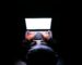 A person in a dark room typing on a laptop, symbolizing privacy, cybersecurity, and technology.